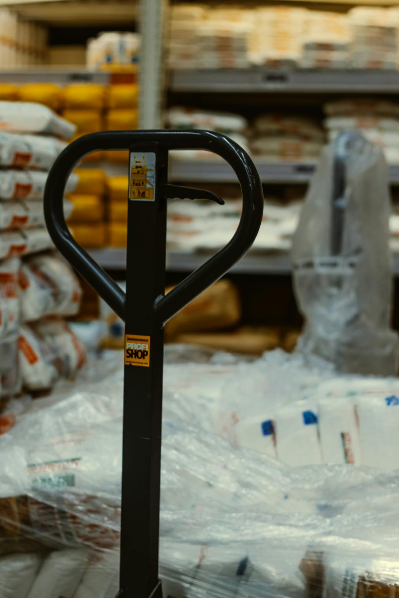Home Pallet truck in an industrial warehouse with stacked goods.